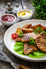 Grilled pork loin steaks with green beans and fried potatoes on wooden table
