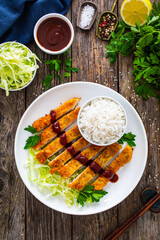 Tonkatsu - crispy Japanese pork chop with white rice and  fresh vegetables on wooden table