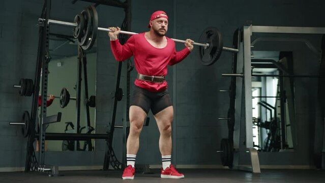 professional bodybuilder squats with a barbell in the gym, dressed in red clothes.slow motion 
