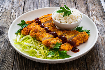 Tonkatsu - crispy Japanese pork chop with white rice and  fresh vegetables on wooden table