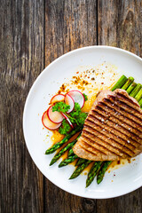 Grilled beef steak with green asparagus on wooden table

