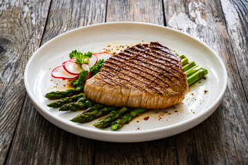 Grilled beef steak with green asparagus on wooden table

