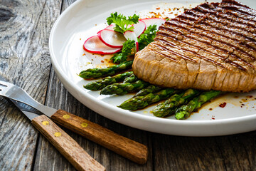 Grilled beef steak with green asparagus on wooden table

