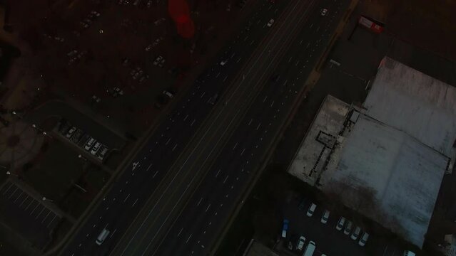Aerial Tilt Up Shot Of Vehicles On Freeway By Bojangles Coliseum, Drone Flying Forward Over City Against Cloudy Orange Sky At Sunset - Charlotte, North Carolina