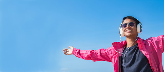 happy and free young man with headphones on blue background