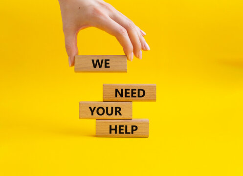 We need your help symbol. Wooden blocks with words We need your help. Beautiful yellow background. Businessman hand. Business and We need your help concept. Copy space.