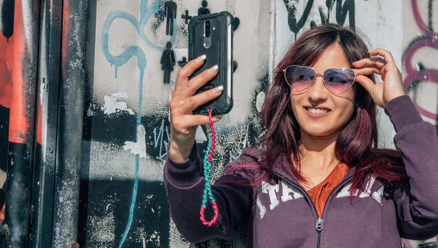 urban woman taking a selfie or live video with the mobile phone
