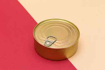 Unopened Tin Can with Blank Edge on Split Red and Beige Background. Canned Food. Aluminum Can for Safe and Long Term Storage of Food. Steel Sealed Food Storage Container