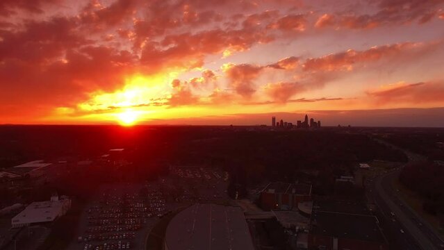 Aerial Shot Of Cars On Freeway By Bojangles Coliseum At Sunset, Drone Flying Backward Over City Against Cloudy Orange Sky - Charlotte, North Carolina