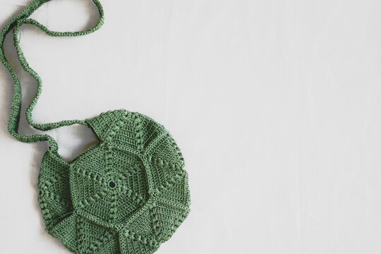 handmade olive green yarn crochet hexagon shape creative bag on white background. copy space for text.