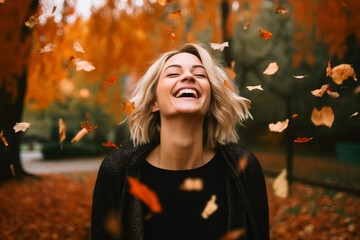 Young beautiful woman laughing amidst falling leaves.