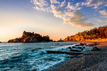 scenic sea shore view of island in ocean with waves and amazing cloudy sunset or sunrise on backgeound