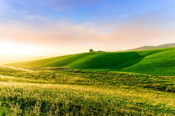 scenery rural view of a contryside farm in green fields and hills with amazing cloudy sky on background