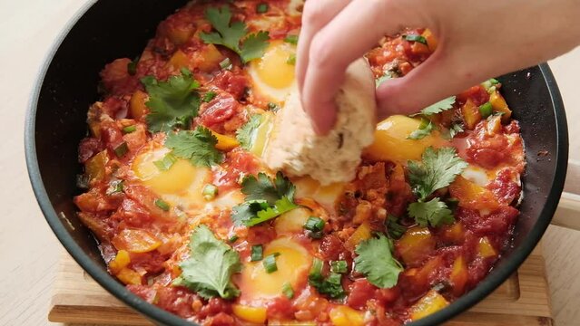 Turkish breakfast recipe menemen step by step. Eggs in a sauce of tomatoes, yellow peppers, garlic, parsley, spices and herbs in pan. Healthy and nutritious breakfast - fried eggs with vegetables