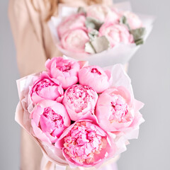 A bouquet of pink peonies in women's hands. Flower delivery. A beautiful bouquet of flowers as a gift for a holiday.