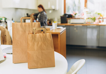 Two Food craft bags on the white table on sunny day. Delivery in any weather around the clock to the client. Fast food eco packaging with big breakfast or diner set
