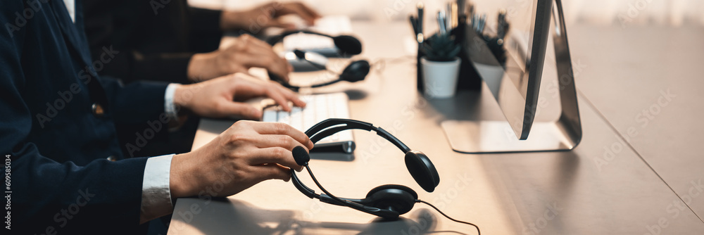 Aufkleber panorama focus hand holding headset on call center workspace desk with blur background of operator t