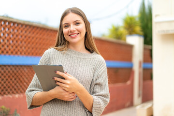 Young pretty blonde woman holding a tablet with happy expression