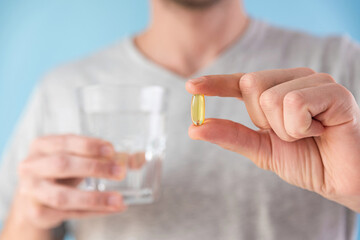 Dietary supplements. Man and holding omega 3 capsule with glass of water. Morning dose of vitamin....