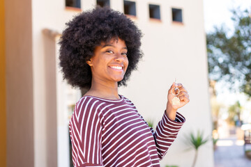 African American girl holding home keys at outdoors smiling a lot