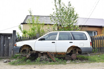 Abandoned old and rusty car on a village street.
