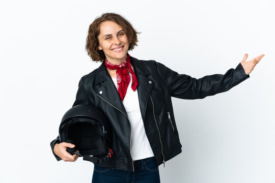 English woman holding a motorcycle helmet isolated on white background extending hands to the side for inviting to come