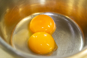Two egg yolks in a steel bowl for making sauce or omelet