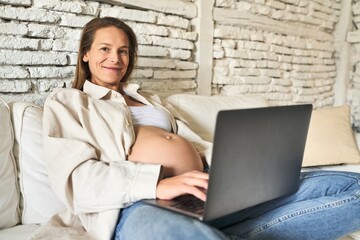 Pregnant woman, serene morning with laptop on sofa