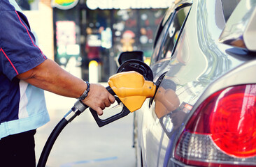 A man uses his hand to open a gasoline or diesel nozzle. To fill a car parked at a gas station with a gasoline or diesel dispenser.