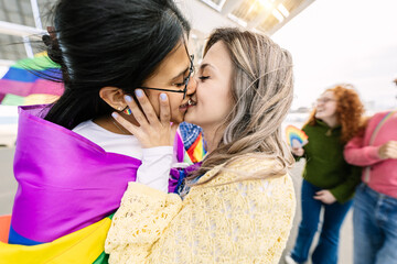 Young female couple in love kissing during gay pride parade festival day. LGTB community people...