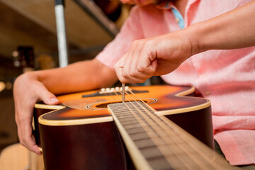 Young musician tuning a classical guitar in a guitar shop