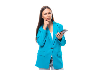 smart stylish young brunette businesswoman in a blue jacket is dialing a call on the phone on a white background with copy space