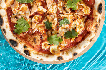 hot pizza on a wooden stand on a blue background water