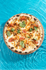 hot pizza on a wooden stand on a blue background water