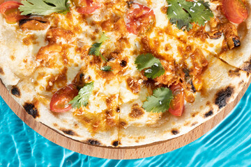 hot pizza on a wooden stand on a blue background water