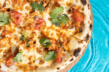 hot pizza on a wooden stand on a blue background water