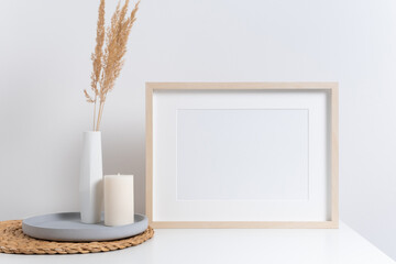Horizontal picture frame mockup in white room with interior decorations, blank wooden frame mock up