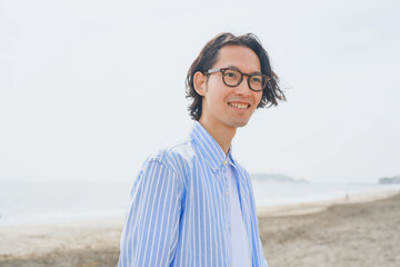 海岸を歩く青いストライプシャツを着た男性