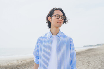 海岸を歩く青いストライプシャツを着た男性