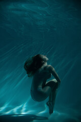 a girl under water, in an aquarium, in a pool in flesh-colored underwear naked swims like a mermaid