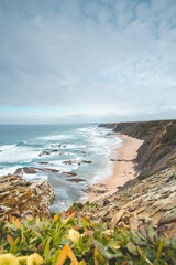 Famous Praia da Carreagem beach in the southwest of Portugal, near the town of Aljezur in the Odemira region. The waves of the Atlantic Ocean crash on the sand. Wandering the Fisherman Trail