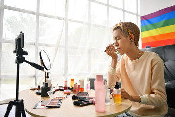 Gay teenager beauty blogger an makeup artist applying and reviewing products while streaming online makeup video tutorial with mobile phone, Use the corrector to line the lower eyelid.