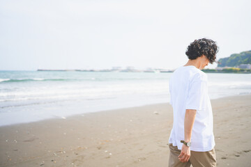 夏の海岸を歩くパーマヘアの男性