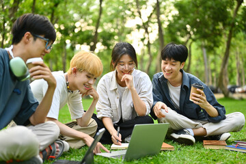 Group of Asian college students sitting in group work on the lawn, outdoors.