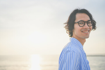 夕陽を背中に橋の上で微笑む男性