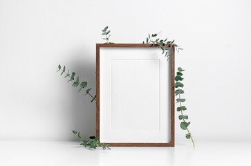 Portrait picture frame mockup in white minimalistic interior with eucalyptus plant decoration,...