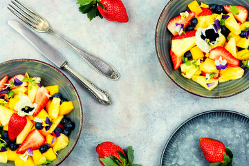 Bright fruit salad with edible flowers.