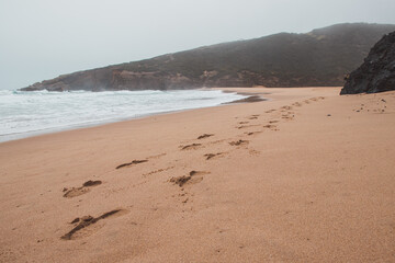 Wandering along the Fisherman Trail in the Algarve region of southwestern Portugal. Human footprints in the sandy surface