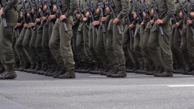 Military men marching in the parade. Soldiers legs. Boots forces and infantry soldier. Army march. Defender team. Crowd man go. Armed forces walking in a row. Uniform. War background. Machine guns