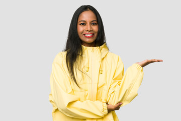Young Indian woman cut out isolated on white background showing a copy space on a palm and holding...